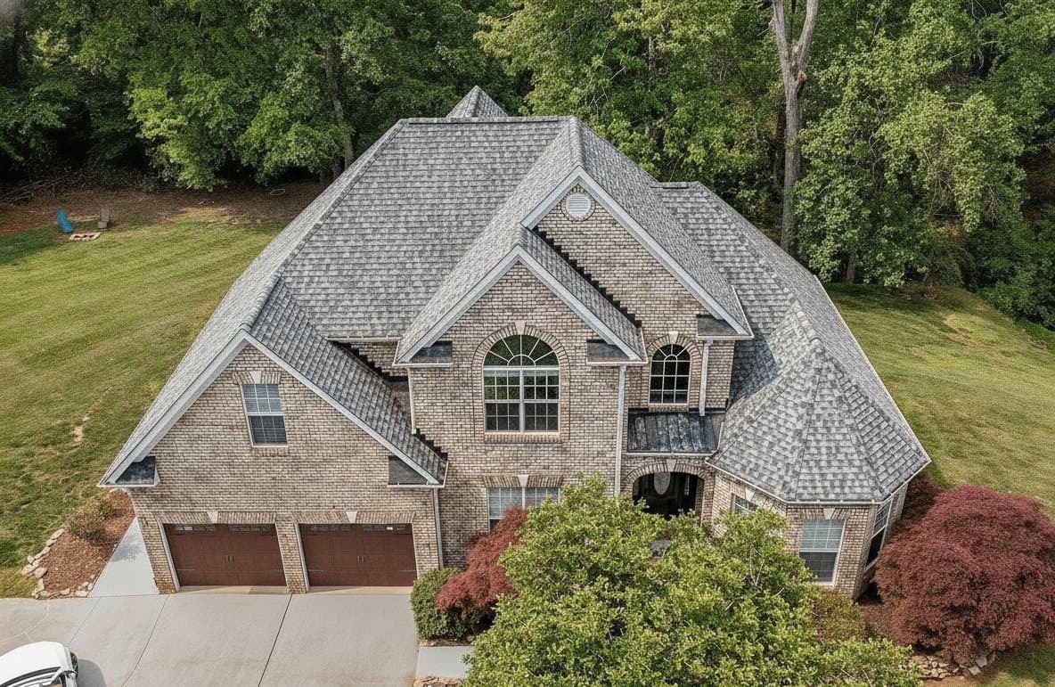 A large custom brick home with a worn, weathered roof before renewal